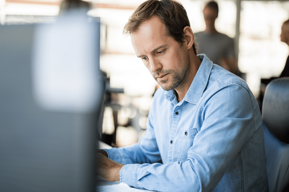 Professional man in blue shirt works at his desk