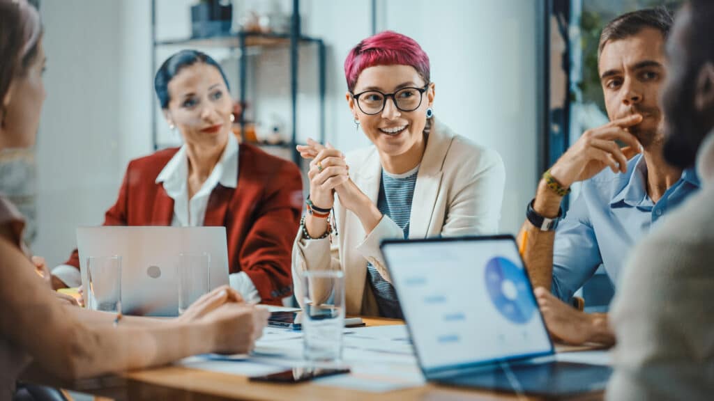 Office Meeting in Conference Room: Specialist with Short Pink Hair Talks about Firm Strategy with Diverse Team of Professional Businesspeople. Creative Start-up Team Discusses Big Project