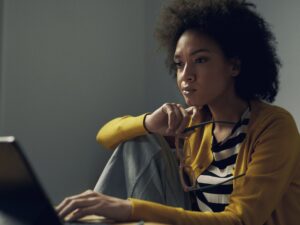 Woman in yellow works on her laptop