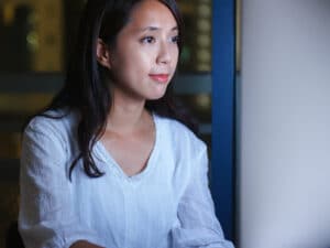 Woman types on keyboard while looking at screen