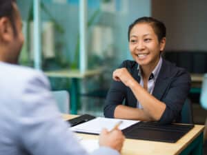 Happy excited businesswoman supporting idea of colleague while they discussing marketing strategy at meeting. Cheerful Asian woman analyzing data with colleague. Teamwork concept