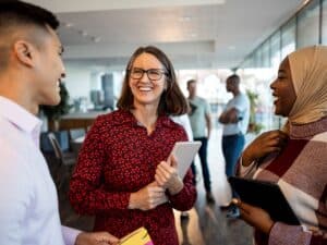 Three people talking and smiling in a modern office