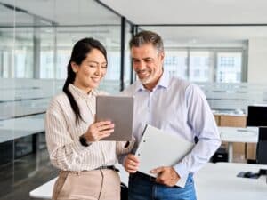 Two smiling people looking at content on a tablet